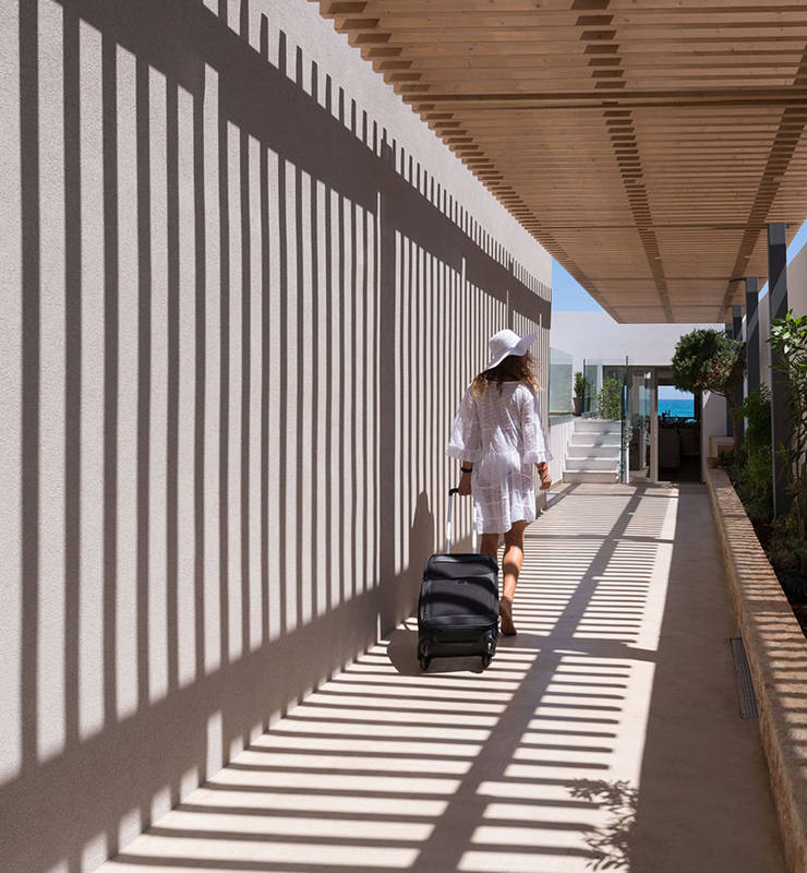 Cactus Bay visitor in white outfit with their suitcase walking in the hotel premises